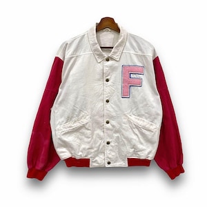 Può includere: Giacca college bianca e rossa con una grande toppa rosa con la lettera "F". La giacca ha una chiusura con bottoni, due tasche anteriori e maniche e finiture rosse. La giacca è appesa a una gruccia di legno.