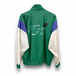 Puede incluir: Chaqueta vintage verde con detalles en blanco y azul. La parte trasera de la chaqueta muestra el texto "FUJICOLOR SUPER ACE 40". Las mangas son blancas, y el cuello y los puños son verdes. Un cortavientos retro.