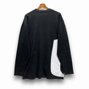 Puede incluir: Camiseta negra de manga larga con un dise&ntilde;o abstracto blanco en el lateral. La camiseta est&aacute; colgada de una percha de madera sobre un fondo blanco. El dise&ntilde;o parece ser de un material reflectante texturizado.
