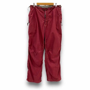 Op de afbeelding: Een rode, lichte broek met een trekkoord en meerdere zakken.