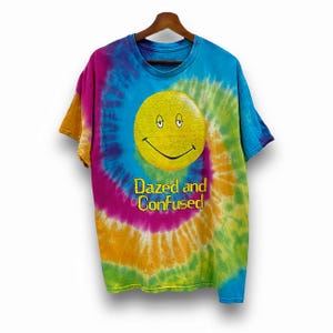 May include: A tie-dye t-shirt with a yellow smiley face and the text "Dazed and Confused".