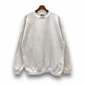 May include: A white crew neck sweatshirt with long sleeves. The sweatshirt has a tag on the front that says "Fruit of the Loom" and "Size M".