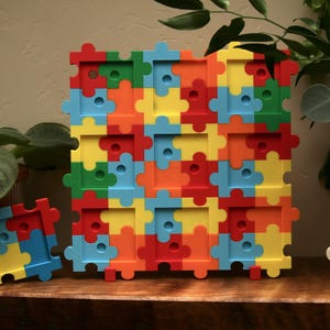 May include: A large square multi-colored puzzle piece display board featuring a grid of nine rectangular cutouts, accompanied by a smaller four-piece puzzle display and a separate black and white four-piece puzzle display, all with circular indentations.
