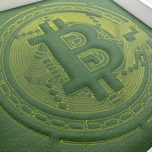May include: A green fabric with a yellow embroidered Bitcoin symbol. The symbol is surrounded by a circular pattern of yellow stitching.