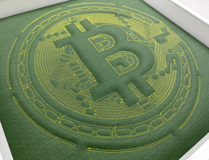 May include: A green fabric with a yellow embroidered Bitcoin symbol. The symbol is surrounded by a circular pattern of yellow stitching.