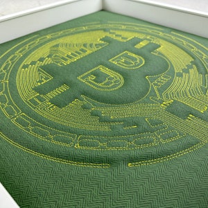 May include: A green fabric pillow with a yellow embroidered Bitcoin logo. The logo is a stylized letter B with circuit board lines.