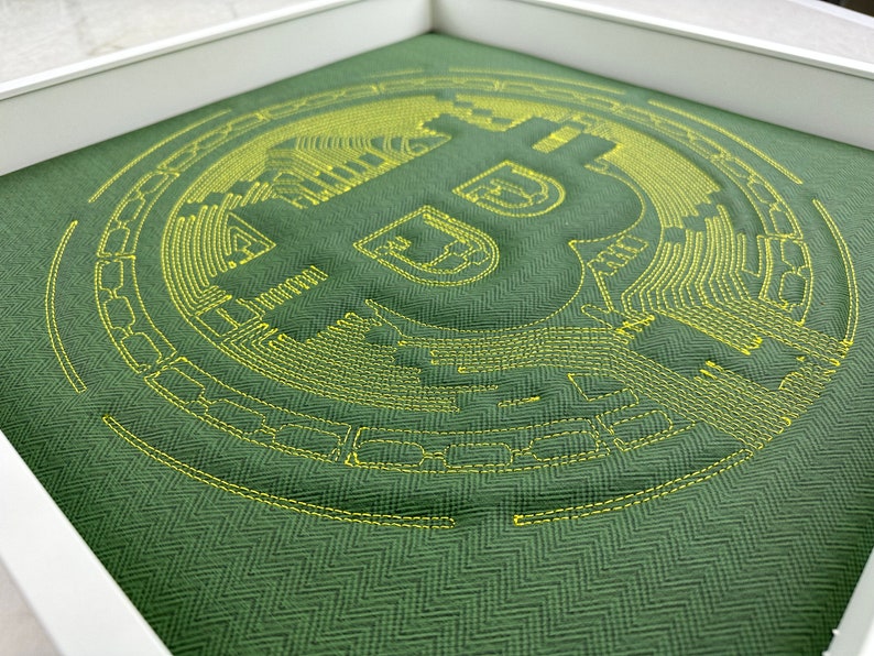May include: A green fabric pillow with a yellow embroidered Bitcoin logo. The logo is a stylized letter B with circuit board lines.