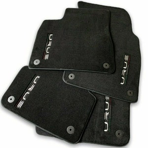 May include: Set of four black car floor mats with the word "URUS" embroidered in white on each mat.