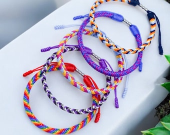 May include: Five colorful braided bracelets with silver beads. The bracelets are made of different colors of thread, including red, orange, yellow, green, blue, purple, and white.
