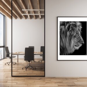 May include: A black and white photograph of a lion's head in profile, framed and hanging on a white wall in a modern office setting.