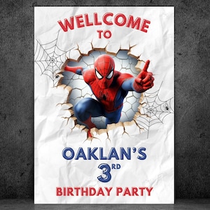 May include: A white poster with the text "WELLCOME TO" in red, and "OAKLAN'S 3RD BIRTHDAY PARTY" in blue and red. The poster features a graphic of Spider-Man breaking through a wall, with spiderwebs in the background.