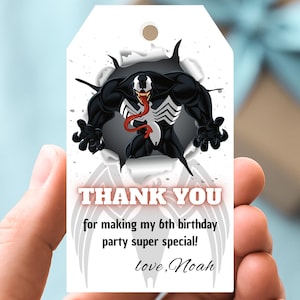 Puede incluir: Etiqueta de regalo blanca con el personaje Venom en blanco y negro rompiendo un agujero. La etiqueta incluye el texto "THANK YOU" y un mensaje personalizado para una fiesta de 6 cumpleaños.