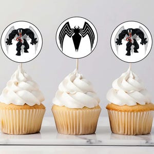 Puede incluir: Tres cupcakes con glaseado blanco cubiertos con toppers redondos de papel comestible para cupcakes que muestran una imagen en blanco y negro de Venom, un superhéroe de Marvel Comics.