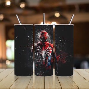 Puede incluir: Tres vasos de acero inoxidable con fondo negro y un gr&aacute;fico de Spiderman rojo y azul. El gr&aacute;fico est&aacute; estilizado con un salpic&oacute;n de pintura roja.