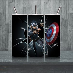 Op de afbeelding: Drie roestvrijstalen bekers met een zwarte achtergrond en een afbeelding van Captain America die een gebarsten glazen raam doorbreekt. De middelste beker toont Captain America's gezicht en de rechter beker toont zijn schild.