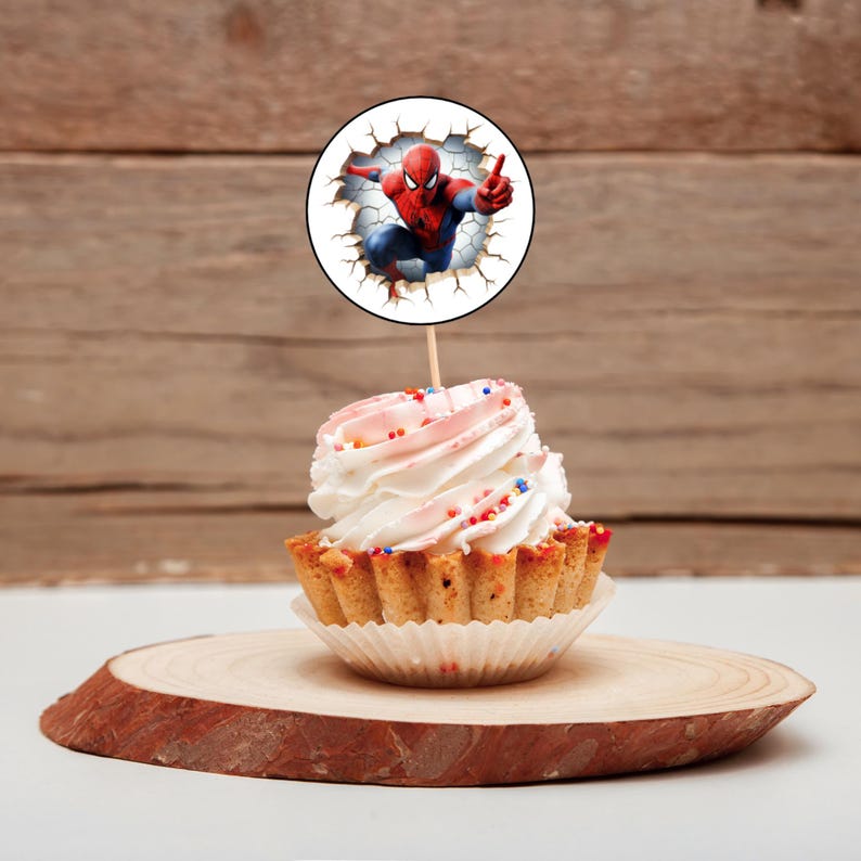 K&ouml;nnte beinhalten: Ein Cupcake mit rosa Frosting und bunten Streuseln, gekr&ouml;nt mit einem runden essbaren Bild von Spiderman, der eine Wand durchbricht.