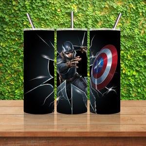 Op de afbeelding: Drie roestvrijstalen bekers met een zwarte achtergrond en een afbeelding van Captain America die door het glas breekt. De afbeelding bevat een close-up van Captain America's gezicht en zijn schild.