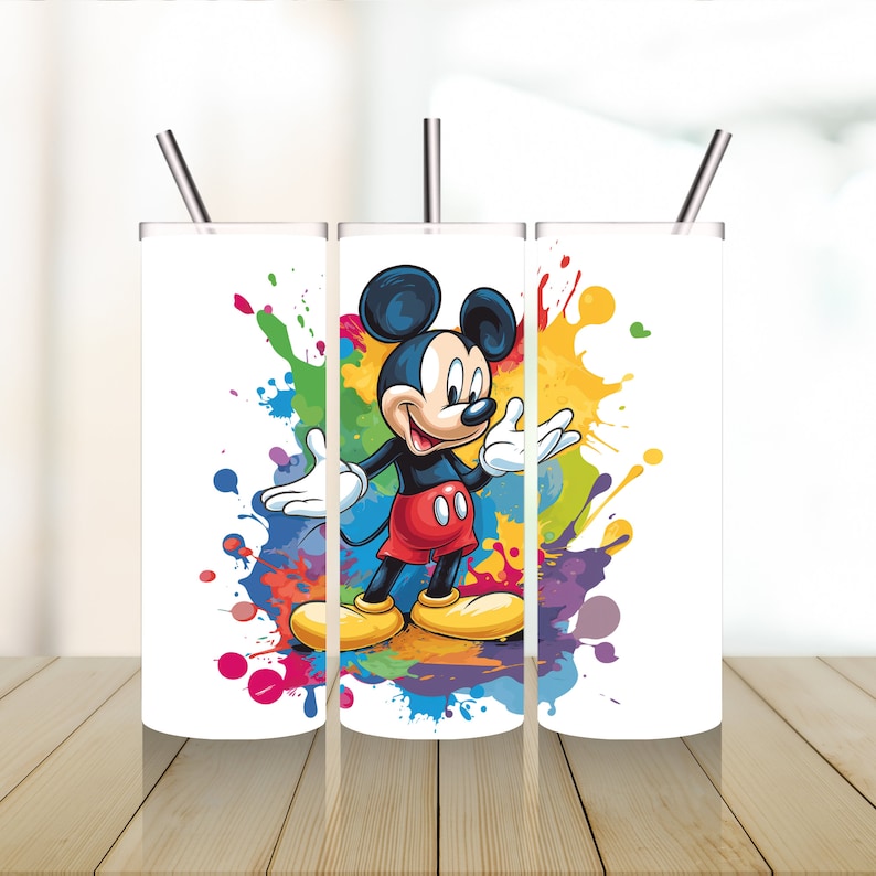 May include: Three white stainless steel tumblers with Mickey Mouse on the middle tumbler. The tumblers have a colourful paint splatter design and come with matching straws.