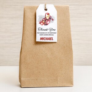 May include: A brown paper gift bag with a white tag. The tag features an Iron Man illustration and the text "Thank You" and "Michael". The tag is attached with a natural twine.
