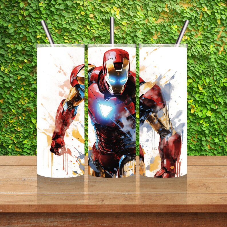 Op de afbeelding: Drie roestvrijstalen bekers met een witte achtergrond en een kleurrijk beeld van Iron Man in een superheldenpose. De afbeelding heeft een aquareleffect met kleurspatten.