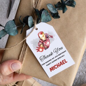 May include: A gift tag with an Iron Man illustration, attached to a wrapped package. The tag reads "Thank You" and "For making my 4th birthday party super special!" with the name "MICHAEL" in red.