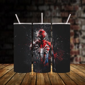Puede incluir: Tres vasos de acero inoxidable con fondo negro y un gr&aacute;fico colorido de Spider-Man con un traje rojo y azul.
