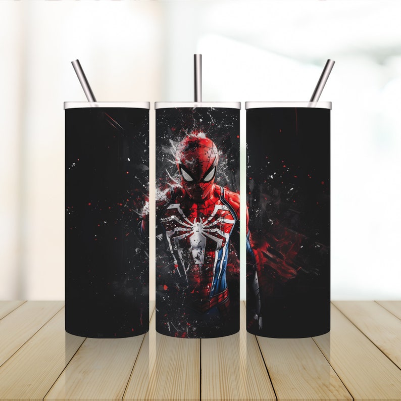 Puede incluir: Tres vasos de acero inoxidable con tapas y pajitas. Los vasos presentan un gr&aacute;fico de Spider-Man con un traje rojo y azul sobre un fondo negro. El fondo tiene salpicaduras de pintura roja y blanca.