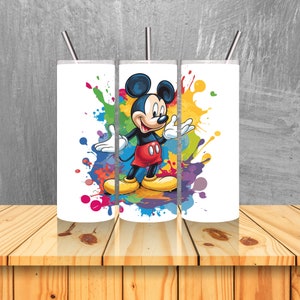 May include: Three white stainless steel tumblers with Mickey Mouse in a colourful paint splatter design. The tumblers have lids and straws.