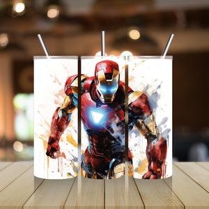 Op de afbeelding: Drie roestvrijstalen bekers met een witte achtergrond en een kleurrijk beeld van Iron Man in een superheldenpose. Het beeld heeft een aquareleffect met spatten van gele, oranje, rode en blauwe verf.