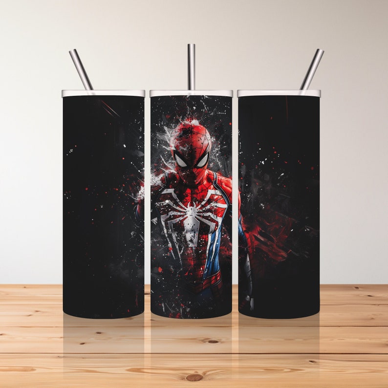 Puede incluir: Tres vasos de acero inoxidable con tapas y pajitas. Los vasos son negros con un gr&aacute;fico de Spider-Man con un traje rojo y azul con un s&iacute;mbolo de ara&ntilde;a negro en el pecho. El fondo es un patr&oacute;n de salpicaduras negro y rojo.