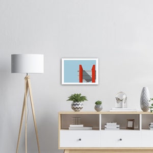 May include: A framed print of a minimalist abstract design featuring a red geometric shape against a light blue background.