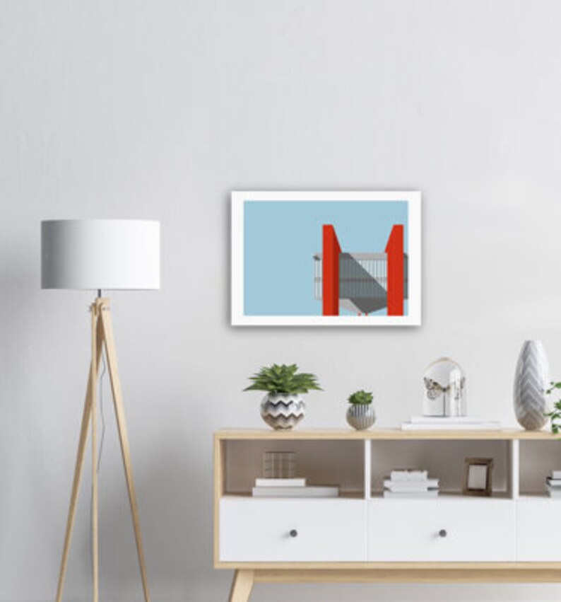May include: A framed print of a minimalist illustration of a building with red accents against a light blue sky.
