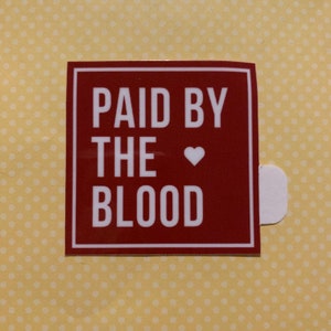 Puede incluir: Una pegatina cuadrada roja con texto blanco que dice "PAID BY THE ♥ BLOOD".