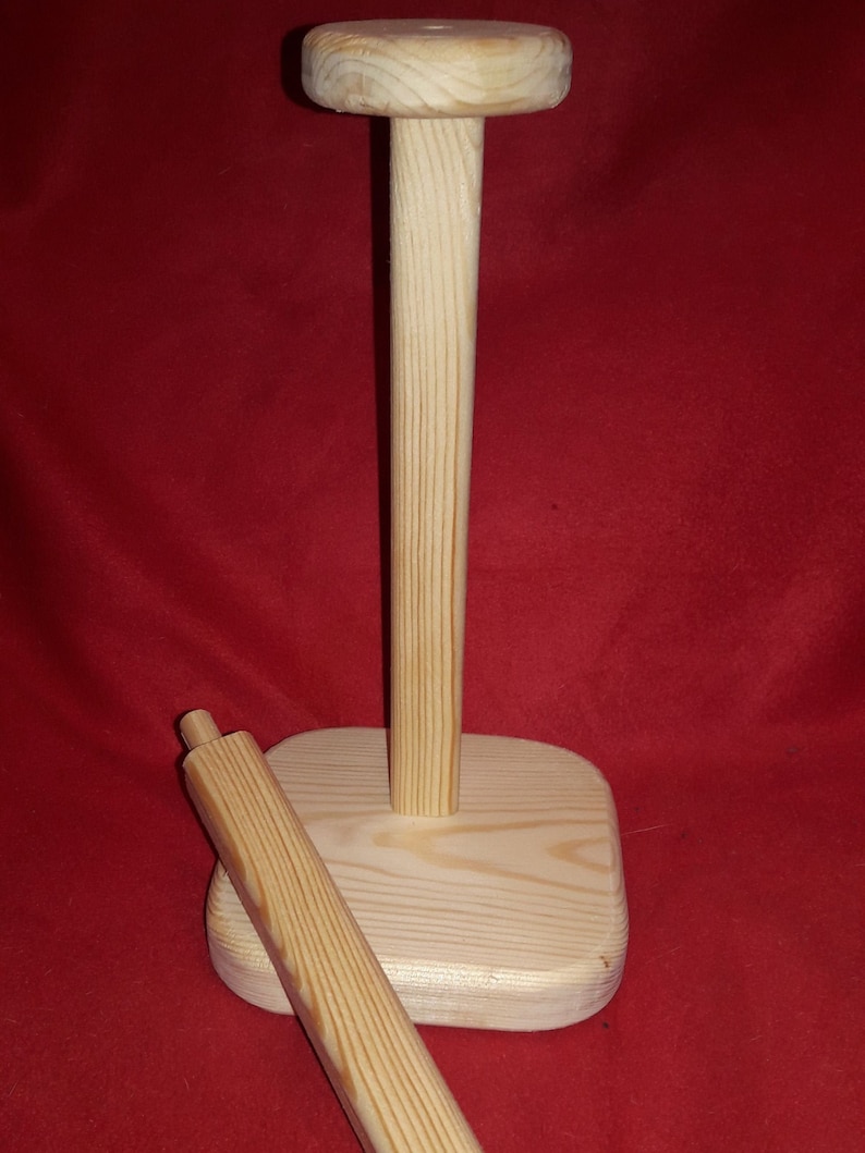 Puede incluir: Un soporte de papel de cocina de madera con una parte superior redonda y una base. El soporte est&aacute; hecho de madera natural y tiene un aspecto r&uacute;stico.