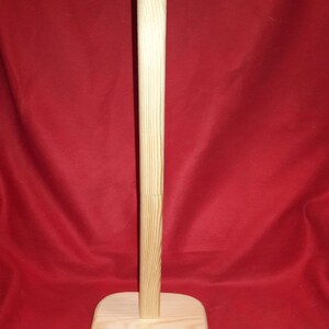 Puede incluir: Un soporte para sombreros de madera con una parte superior redonda y una base cuadrada. El soporte est&aacute; hecho de madera natural y tiene un color marr&oacute;n claro.