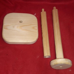 Puede incluir: Porta rollo de papel de cocina de madera sin montar. El soporte consta de una base cuadrada, dos clavijas verticales y una pieza superior redonda. La madera no est&aacute; acabada y tiene un color natural.