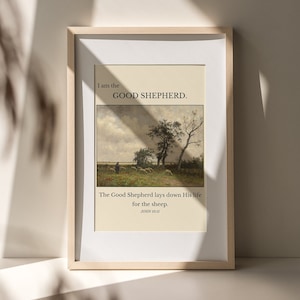May include: A framed print with a beige background and a painting of a shepherd with sheep in a field. The text "I am the GOOD SHEPHERD." is at the top of the print. Below the painting is the text "The Good Shepherd lays down His life for the sheep. JOHN 10:11"