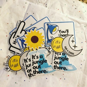 May include: A set of colorful stickers with various designs, including a sunflower, a lamp, a moon, and a hand with the text "Ho's" on it. The stickers also feature the text "It's a jungle out there." and "You'll thank it's a gift. And a curse."