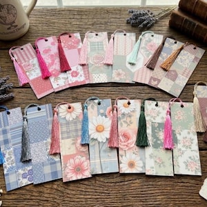 May include: A collection of decorative bookmarks with tassel accents. The bookmarks feature floral, patchwork, and patterned designs in pastel colors. Each bookmark has a different color tassel, including pink, blue, green, and brown.