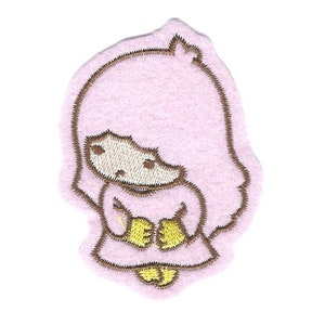 Könnte beinhalten: Ein rosa Filzaufnäher mit einem gestickten Cartoon-Charakter mit hellbraunen Konturen. Der Charakter hat ein hellbraunes Gesicht, Haare und Hände und hält ein gelbes Objekt. Auf weißem Hintergrund.