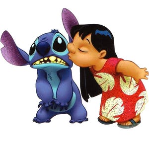 Op de afbeelding: Een cartoon illustratie van Lilo die Stitch kust. Stitch is een blauwe alien met grote oren en een humeurige uitdrukking. Lilo draagt een rode jurk met witte bladeren. De achtergrond is wit.