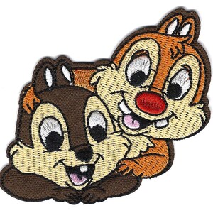 May include: Embroidered patch featuring Chip and Dale, the Disney chipmunk duo. The patch shows the two characters in a friendly embrace, with Chip in brown and Dale in orange. The patch has a brown border and is suitable for clothing or accessories.