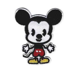 Könnte beinhalten: Ein Cartoon-Patch mit Mickey Mouse. Die Figur hat große schwarze Ohren, ein weißes Gesicht und eine schwarze Umrandung. Er trägt rote Shorts, gelbe Schuhe und schwarze Handschuhe. Für Kleidung oder Accessoires.