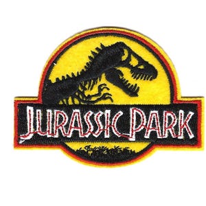 May include: Embroidered patch featuring the Jurassic Park logo. The design includes a yellow background with a black dinosaur skeleton silhouette, the words "JURASSIC PARK" in white, and a red border.