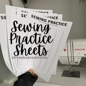 Puede incluir: Una pila de hojas blancas de "Sewing Practice Sheets" con líneas punteadas para practicar la costura recta. Las hojas se sostienen frente a una máquina de coser Singer blanca. También se ve el texto "@threebearsnaturals".