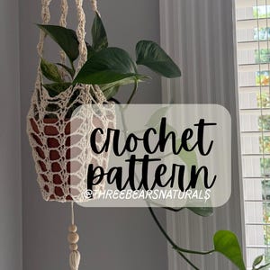 May include: A cream-colored crochet plant hanger with a potted plant inside. The plant has green leaves. The text "crochet pattern" and "@THREEBEARSNATURALS" are visible on the image.