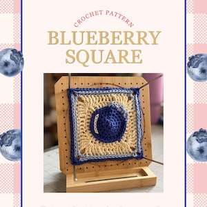 May include: A crochet pattern for a "Blueberry Square" is displayed on a wooden blocking board. The square features a blueberry design in shades of blue and beige. The background has a pink and white checkered pattern with blueberry illustrations.