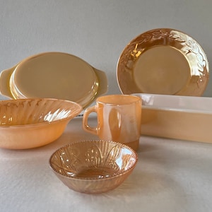 May include: A set of six vintage milk glass dishes in a peach color. The set includes a large bowl, a small bowl, a casserole dish, a mug, and two plates.