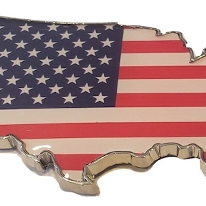May include: A silver-colored metal outline of the United States of America with a red, white, and blue American flag design.