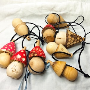 Peut inclure: Une collection d'ornements en bois en forme de champignon avec des dessus à pois rouges et blancs. Les ornements sont enfilés ensemble avec des cordons noirs et ont un aspect rustique et fait main.